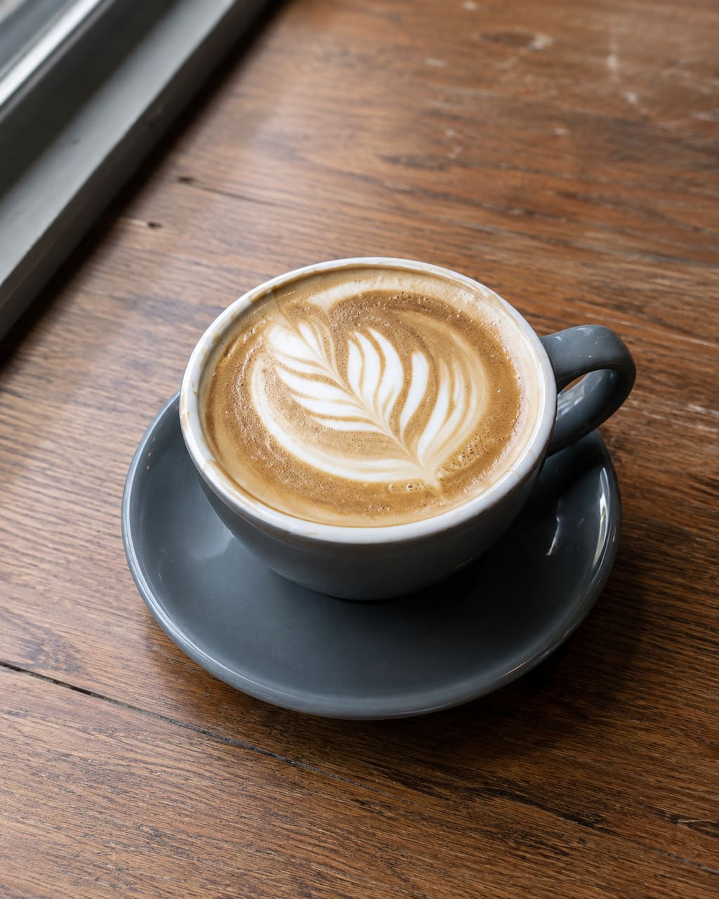 The same flat white, photographed properly: moved to the window table, shot from just above the cup, table cleared, latte art square in frame.