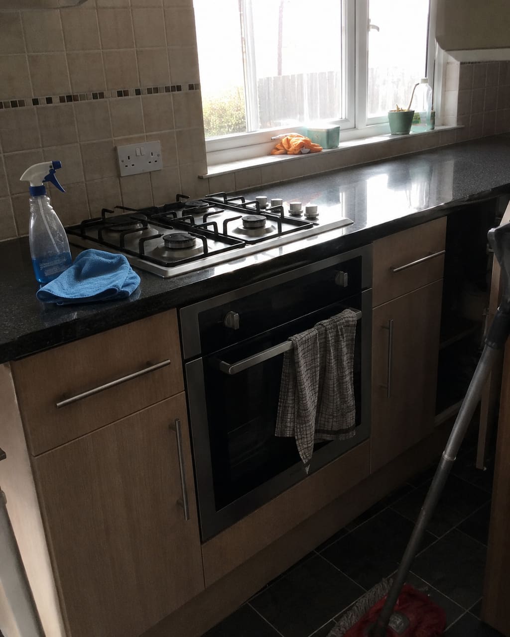 The photograph most cleaners take: a finished kitchen shot in a hurry from the doorway, tilted, worktop lost in the shadow of the wall units.